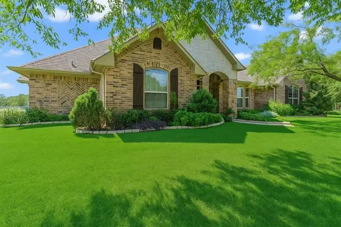 a front view of a house with a yard and trees