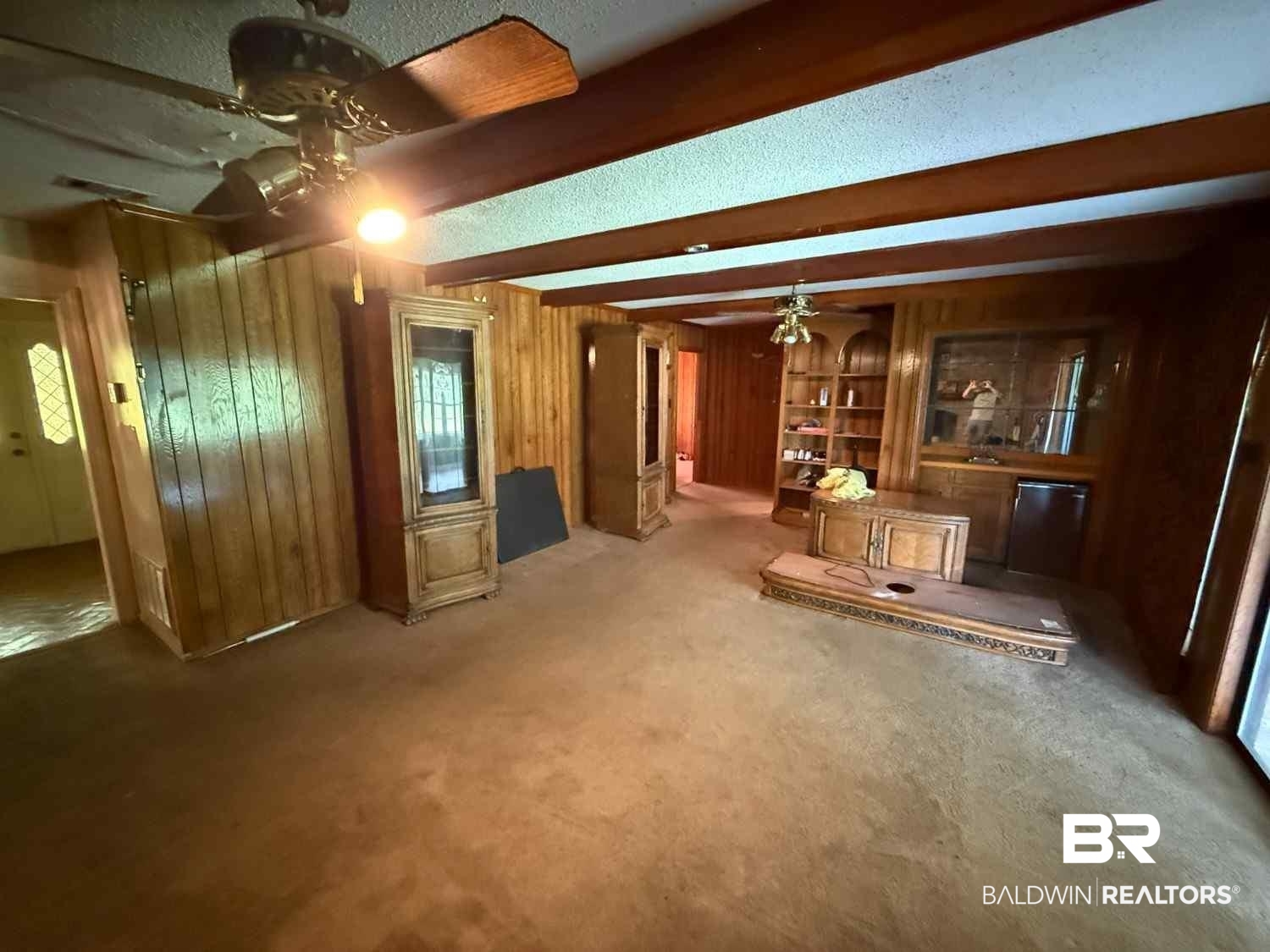 3721 Robertson Court Mobile, AL 36693 - Photo 15 of 22 Unfurnished living room with beamed ceiling, wooden walls, a ceiling fan, and carpet floors