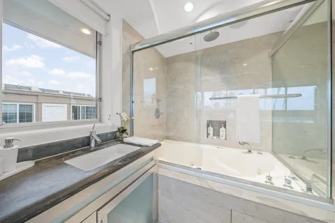 a bathroom with a granite countertop sink mirror and a bath tub