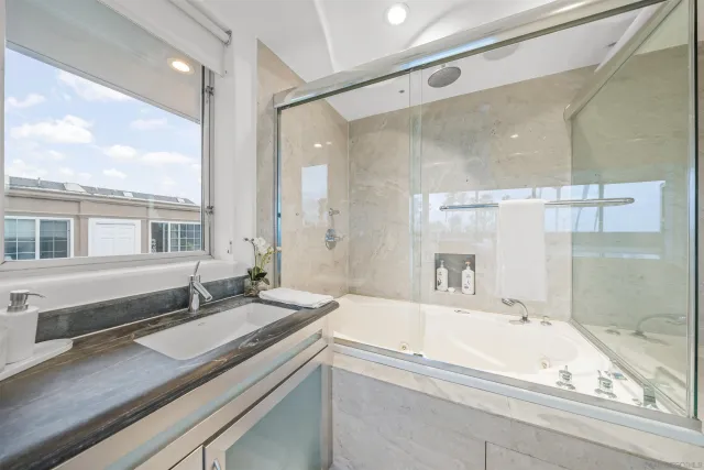 a bathroom with a granite countertop sink mirror and a bath tub