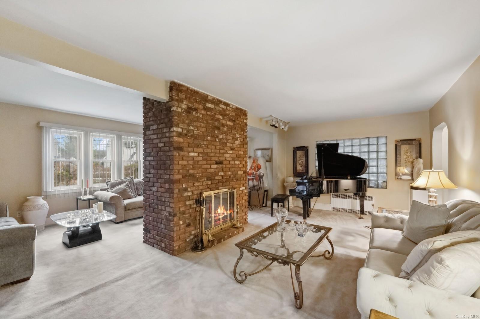 32 Harvard Avenue Hewlett, NY 11557 - Photo 9 of 42 Carpeted living room with beamed ceiling and a brick fireplace