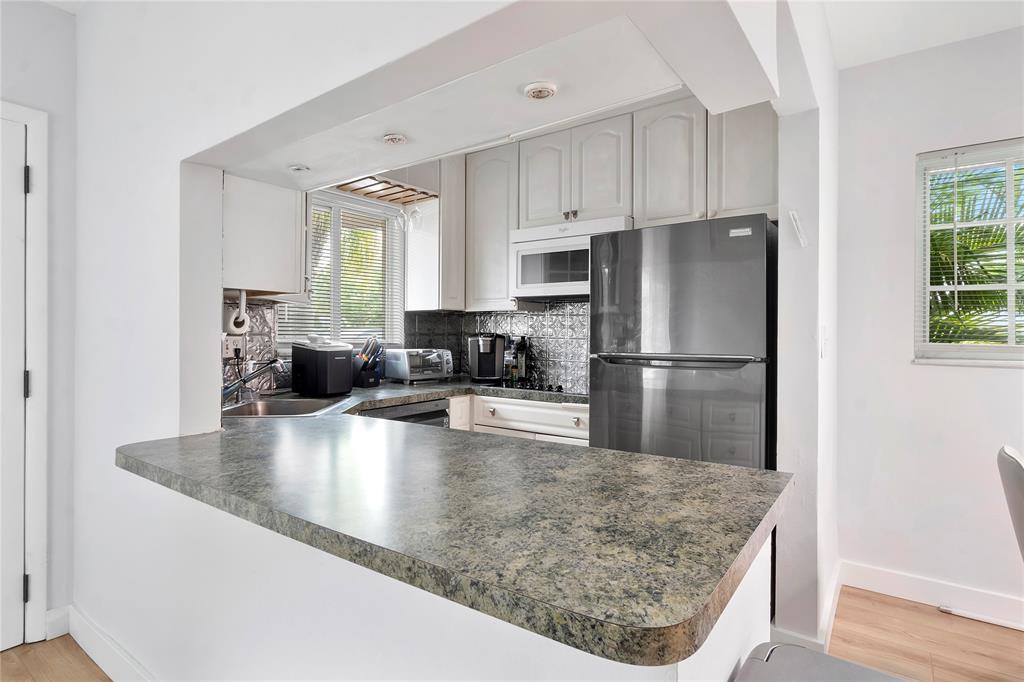 3030 Northeast 5th Terrace, Unit 1 Wilton Manors, FL 33334 - Photo 2 of 22 a kitchen with kitchen island a counter top space a sink and refrigerator