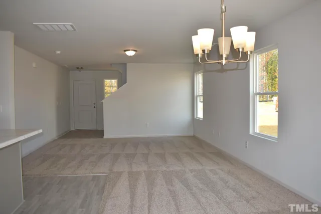 an empty room with wooden floor chandelier and windows