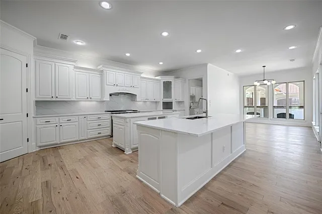 a large kitchen with stainless steel appliances a large counter top a sink and a refrigerator