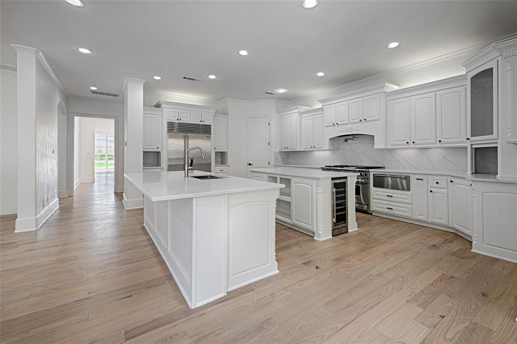 6301 Churchill Way Dallas, TX 75230 - Photo 19 of 40 a large kitchen with stainless steel appliances granite countertop a stove top oven a sink a refrigerator and white cabinets with wooden floor