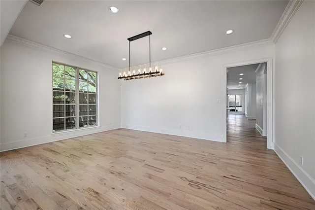 an empty room with wooden floor and chandelier