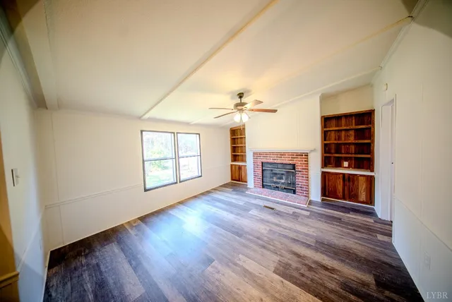an empty room with wooden floor fireplace and windows