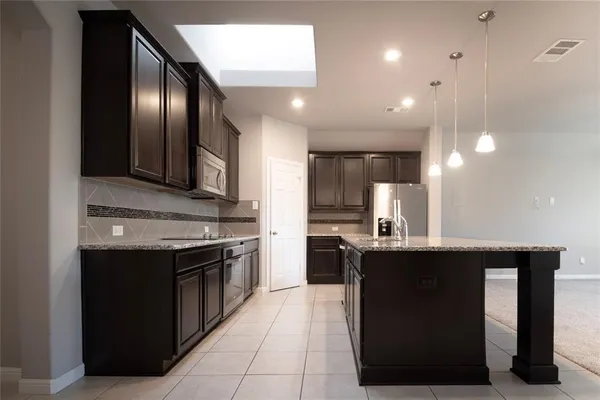 a kitchen with stainless steel appliances granite countertop a sink a stove and refrigerator