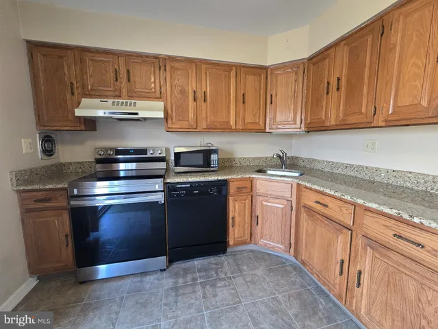 a kitchen with granite countertop a stove top oven sink and cabinets