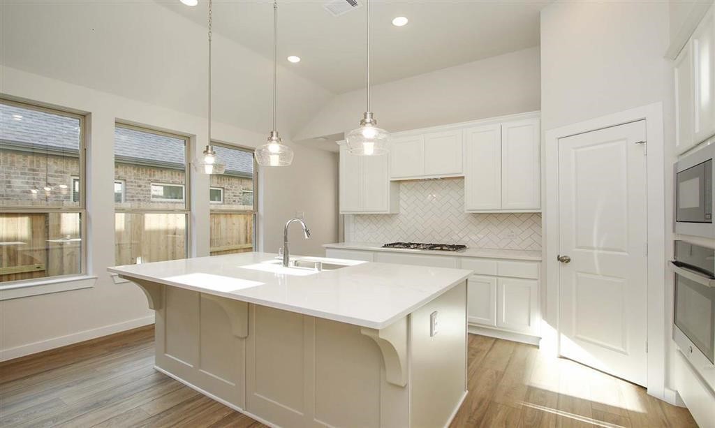 21582 Jordan Pond Ridge Porter, TX 77365 - Photo 3 of 21 a kitchen with a stove a sink a refrigerator and white cabinets with wooden floor