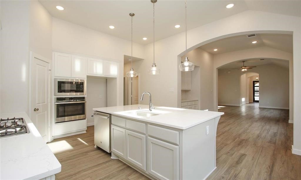21582 Jordan Pond Ridge Porter, TX 77365 - Photo 5 of 21 a large white kitchen with a large center island wooden floor and stainless steel appliances