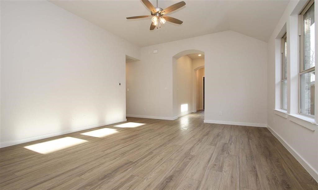 21582 Jordan Pond Ridge Porter, TX 77365 - Photo 9 of 21 an empty room with wooden floor a ceiling fan and windows