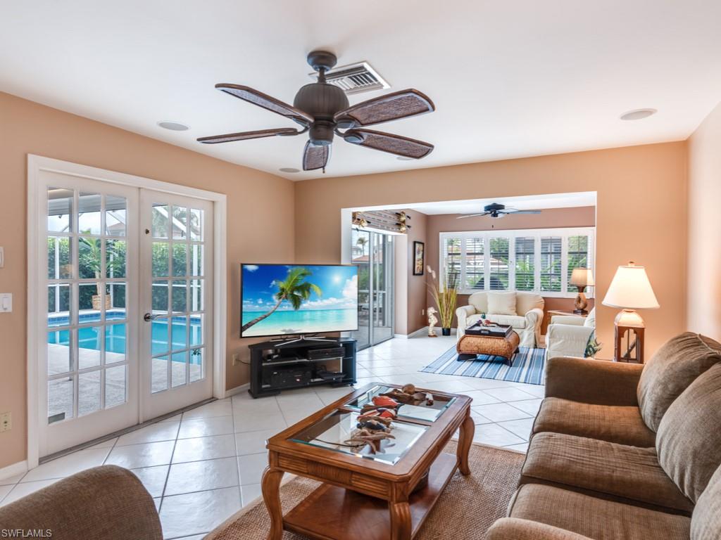 1820 Kingfish Road Naples, FL 34102 - Photo 9 of 20 a living room with furniture a flat screen tv and a floor to ceiling window