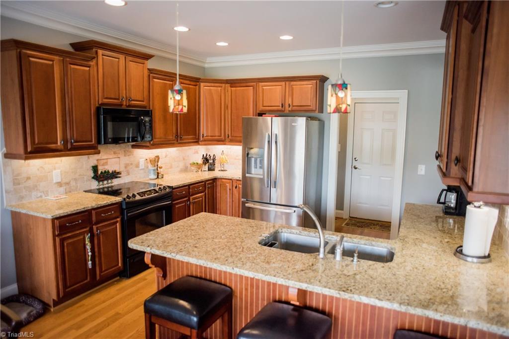 1743 Diercrest Street Oak Ridge, NC 27310 - Photo 11 of 30 Cherry cabinetry, granite counter tops, tiled backsplash, lots of recessed lighting & pendant lighting make for a great kitchen.
