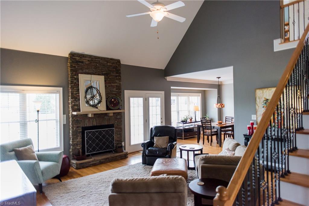 1743 Diercrest Street Oak Ridge, NC 27310 - Photo 7 of 30 Family room features hardwood flooring, a vaulted ceiling with fan, & stacked stone fireplace.