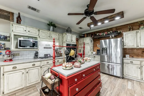 a large kitchen with stainless steel appliances granite countertop a stove oven a refrigerator a dining table and chairs with wooden floor