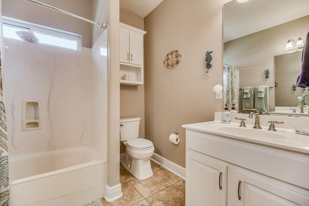 2655 Masters Boulevard Navarre, FL 32566 - Photo 35 of 87 a bathroom with a sink toilet a mirror a bathtub and shower