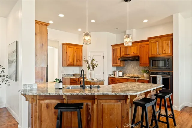 a kitchen with stainless steel appliances granite countertop a sink a stove and a wooden floors