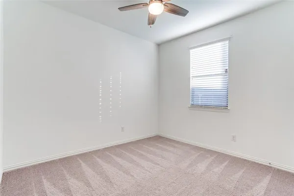 an empty room with a chandelier fan and windows