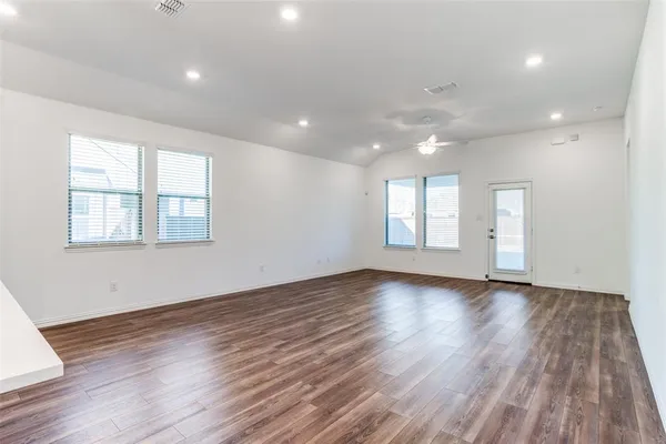 a view of an empty room with wooden floor and window