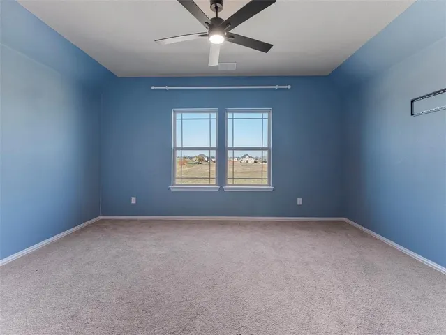 a view of a big room with a ceiling fan and windows