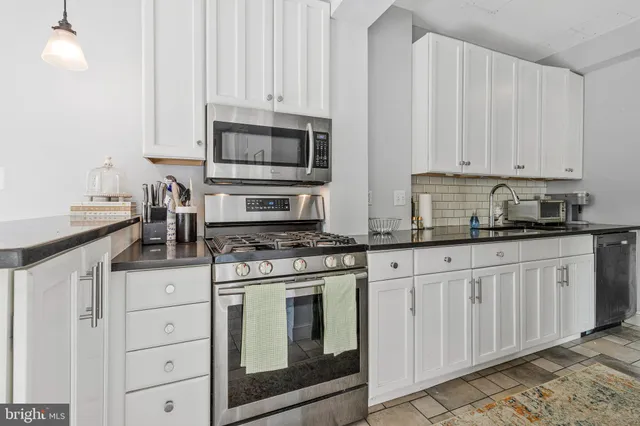 a kitchen with stainless steel appliances granite countertop white cabinets a sink and dishwasher