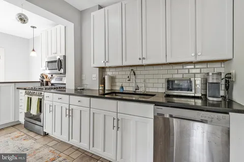 a kitchen with stainless steel appliances granite countertop a sink a stove and a refrigerator