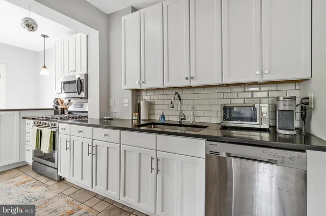 a kitchen with stainless steel appliances granite countertop a sink a stove and a refrigerator