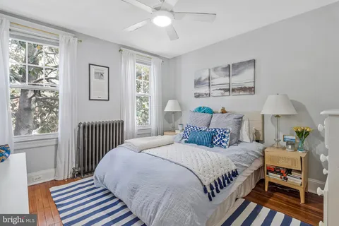 a bedroom with a bed a dresser and next to a window