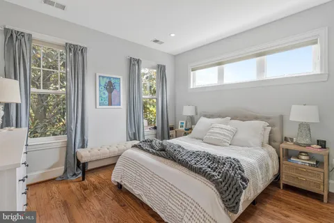 a bedroom with a bed a table and windows