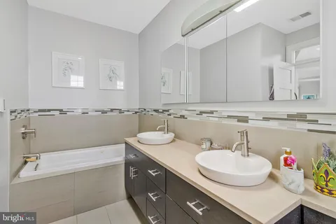 a bathroom with a granite countertop sink a mirror and a bathtub
