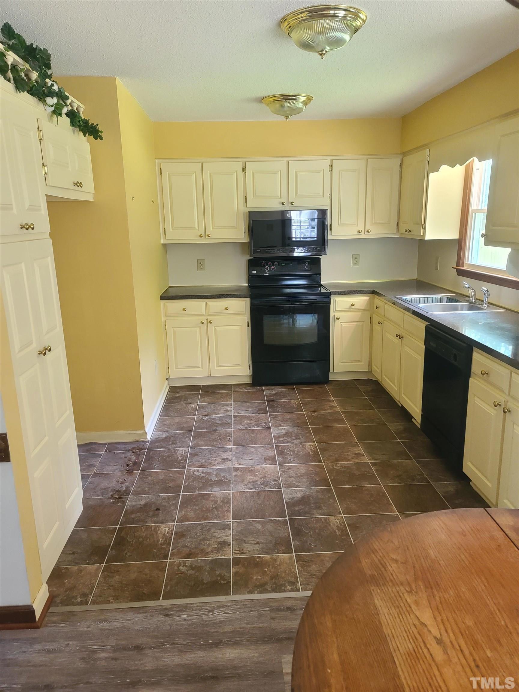 13125 Callens Lane Willow Spring, NC 27592 - Photo 5 of 13 a kitchen with granite countertop a stove a sink a refrigerator a window and cabinets