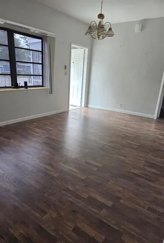 an empty room with wooden floor chandelier fan and windows