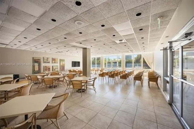 a room with lots of tables a large window and chairs