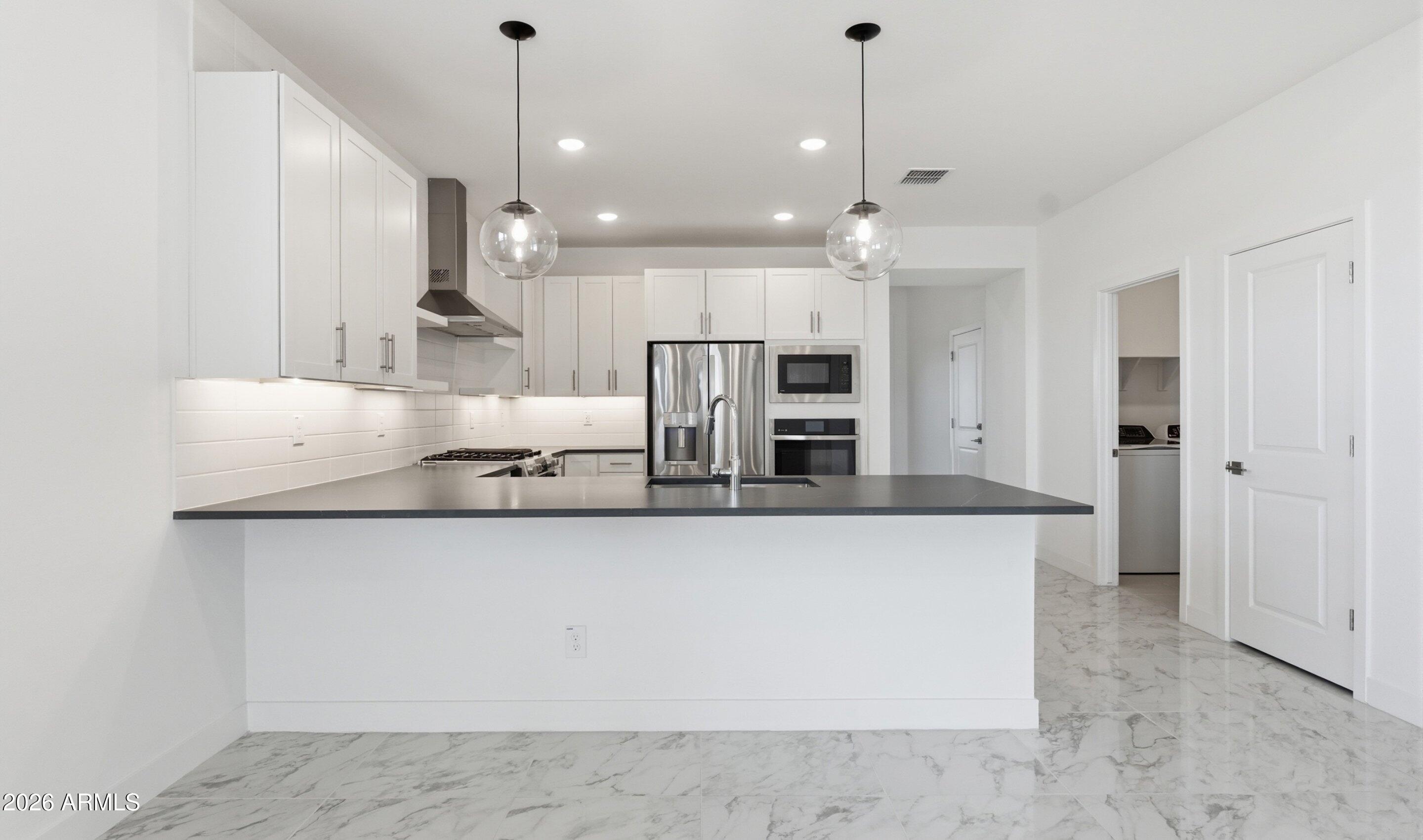 7779 West Sands Road Glendale, AZ 85303 - Photo 6 of 37 a large kitchen with stainless steel appliances a large counter top a stove a refrigerator and a sink
