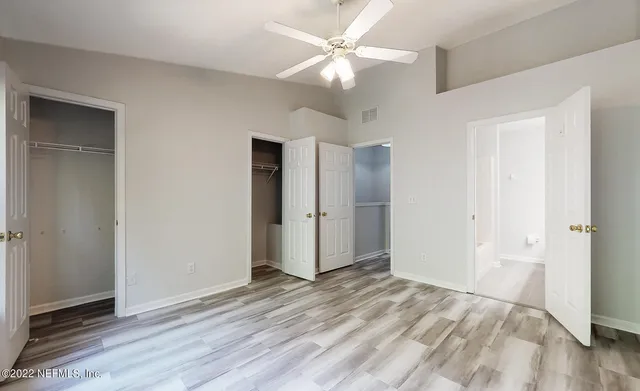 an empty room with wooden floor and a ceiling fan