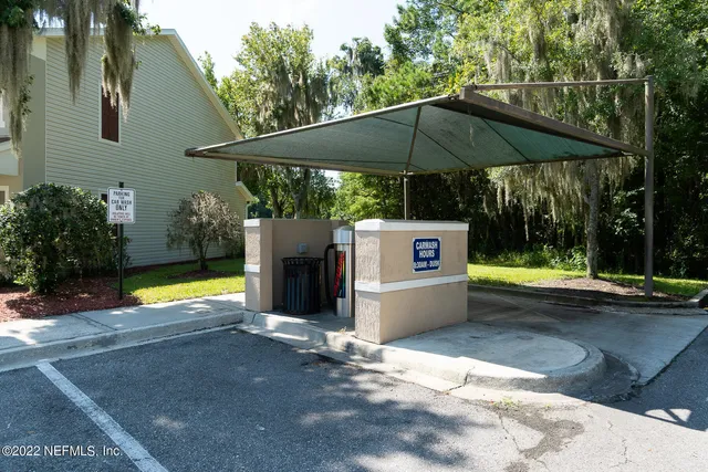 a view of pool with lawn chairs under an umbrella