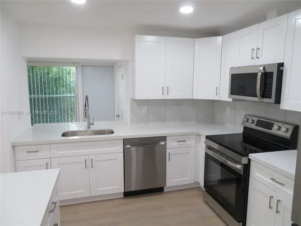 a kitchen with cabinets appliances a sink and a window
