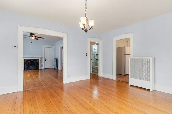 a view of a livingroom with wooden floor a ceiling fan and windows