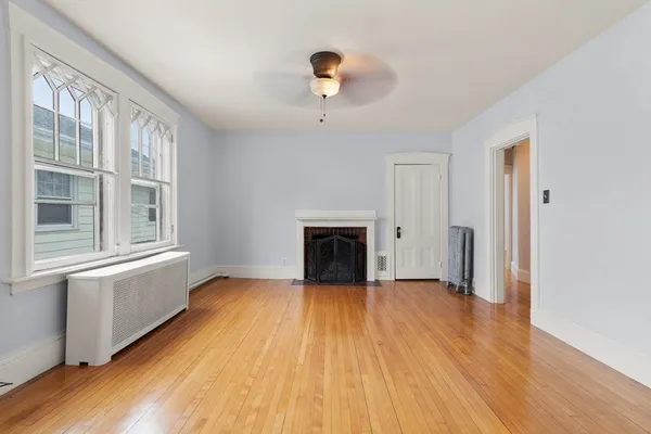 a view of empty room with wooden floor and fireplace
