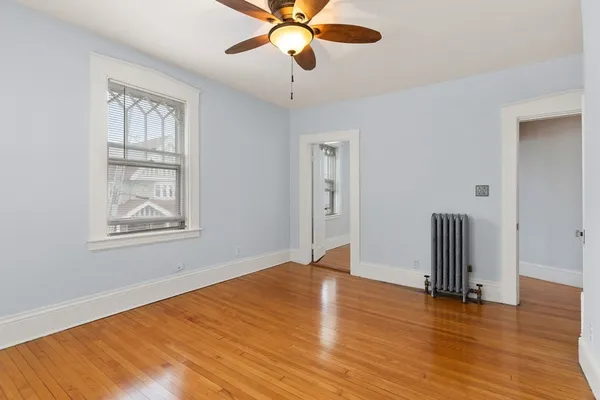 a view of an empty room with window and wooden floor