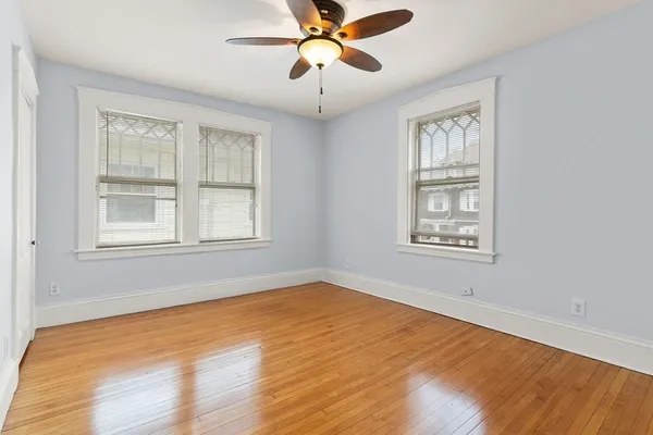 a view of an empty room with window and a chandelier fan