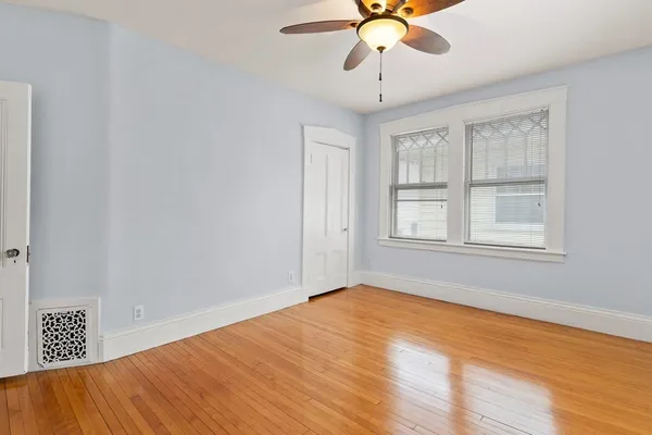 a view of an empty room with window and wooden floor
