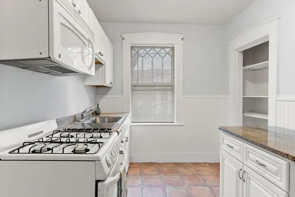 a kitchen with granite countertop a sink stove and cabinets