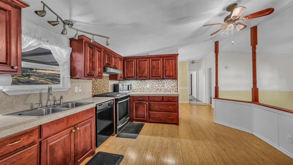 1240 Riverview Road Millsap, TX 76066 - Photo 20 of 36 a kitchen with stainless steel appliances granite countertop wooden cabinets a stove a sink and a wooden floor