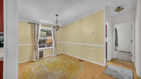 an empty room with chandelier fan and windows