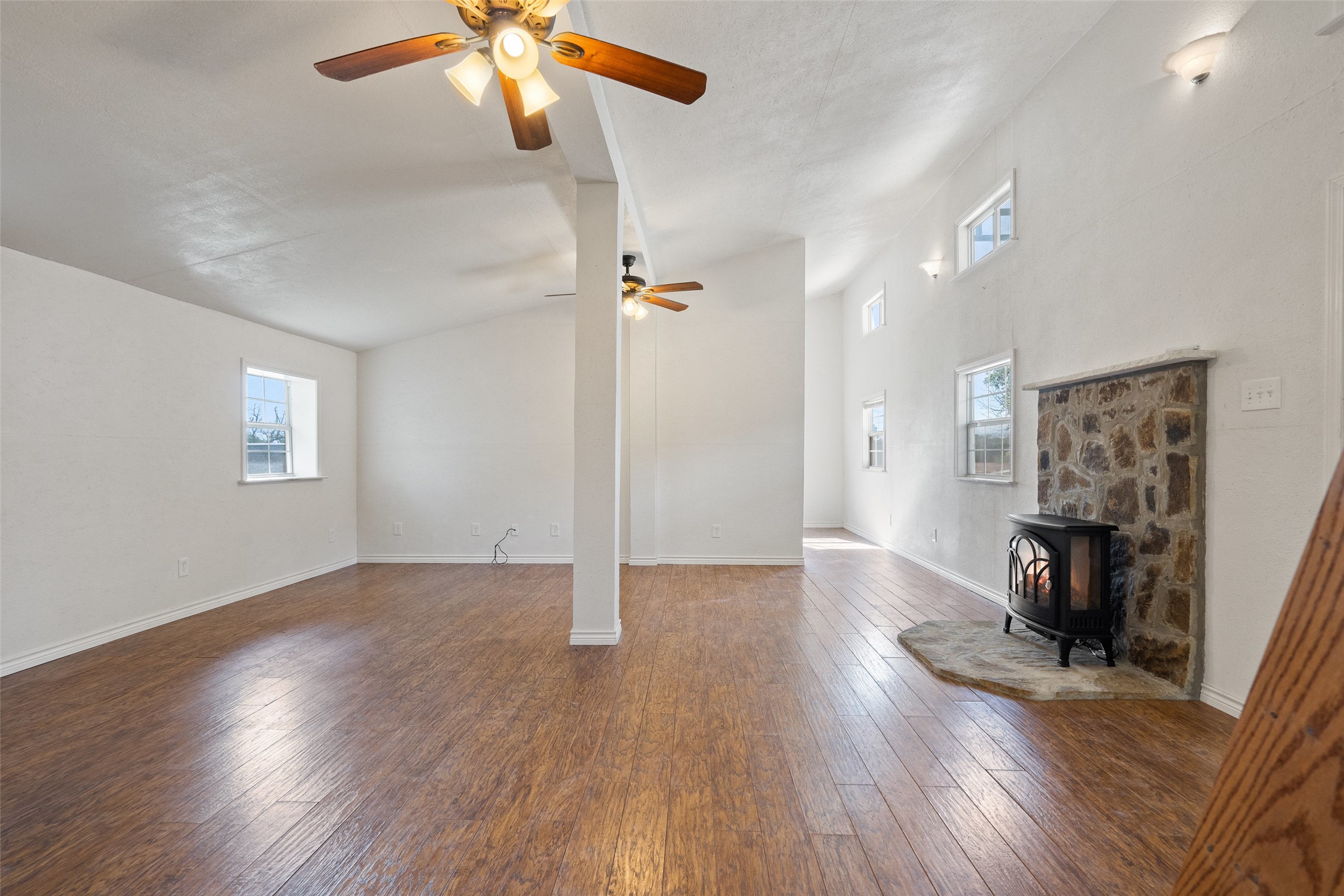 1401 Pursley Road Dripping Springs, TX 78620 - Photo 22 of 35 Guest house living room featuring a wood stove, dark wood-type flooring, plenty of natural light, vaulted ceiling, and a ceiling fan
