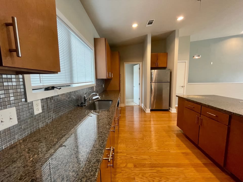 1702 South Lamar Boulevard, Unit 2 Austin, TX 78704 - Photo 4 of 25 Kitchen with dark stone counters, freestanding refrigerator, backsplash, light wood-style floors, and brown cabinetry