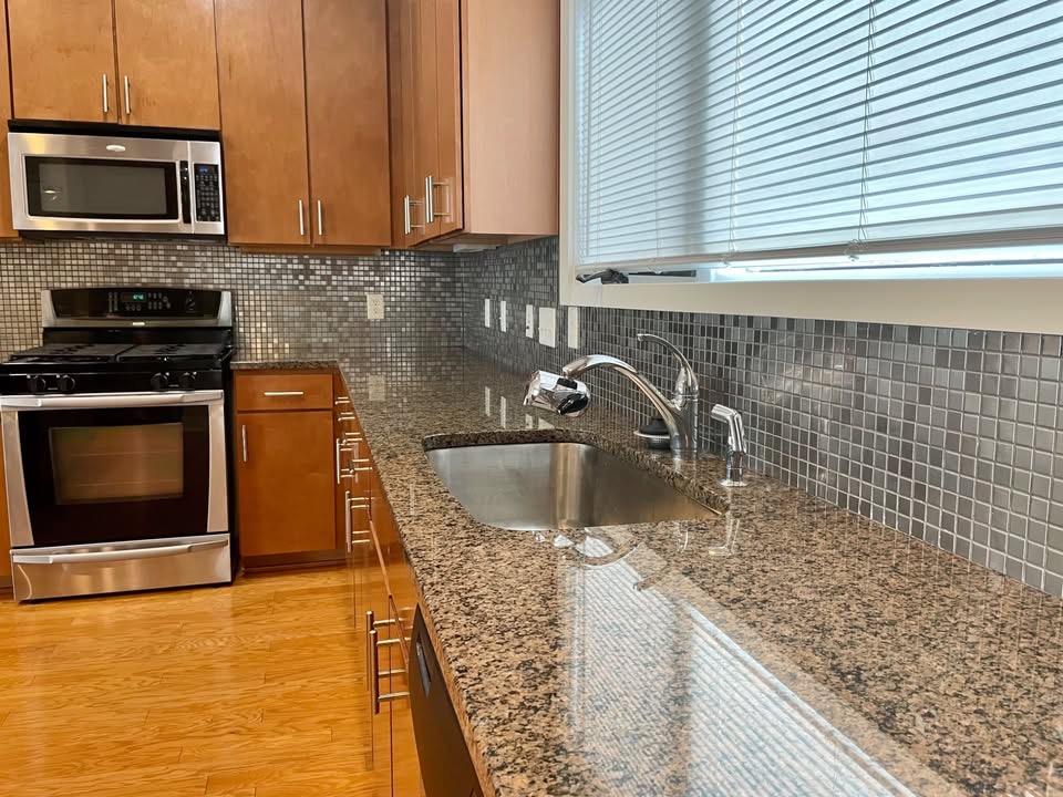 1702 South Lamar Boulevard, Unit 2 Austin, TX 78704 - Photo 5 of 25 Kitchen with appliances with stainless steel finishes, dark stone counters, brown cabinets, and backsplash