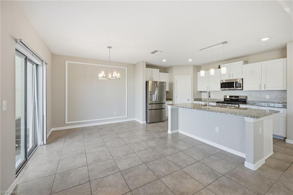 9612 Lemon Drop Loop Sun City Center, FL 33573 - Photo 5 of 33 a kitchen with granite countertop a refrigerator and white cabinets